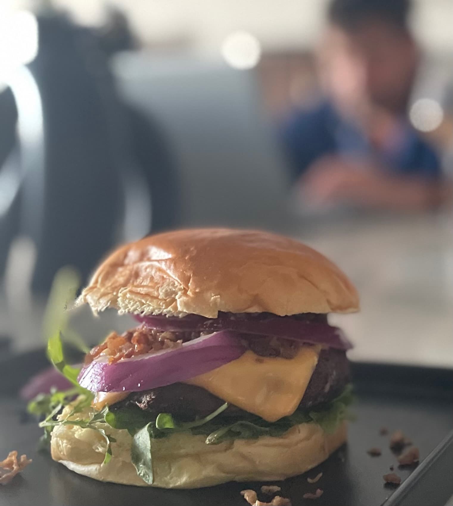 Juicy beef burger topped with melted cheese, red onion, and arugula on a toasted bun.