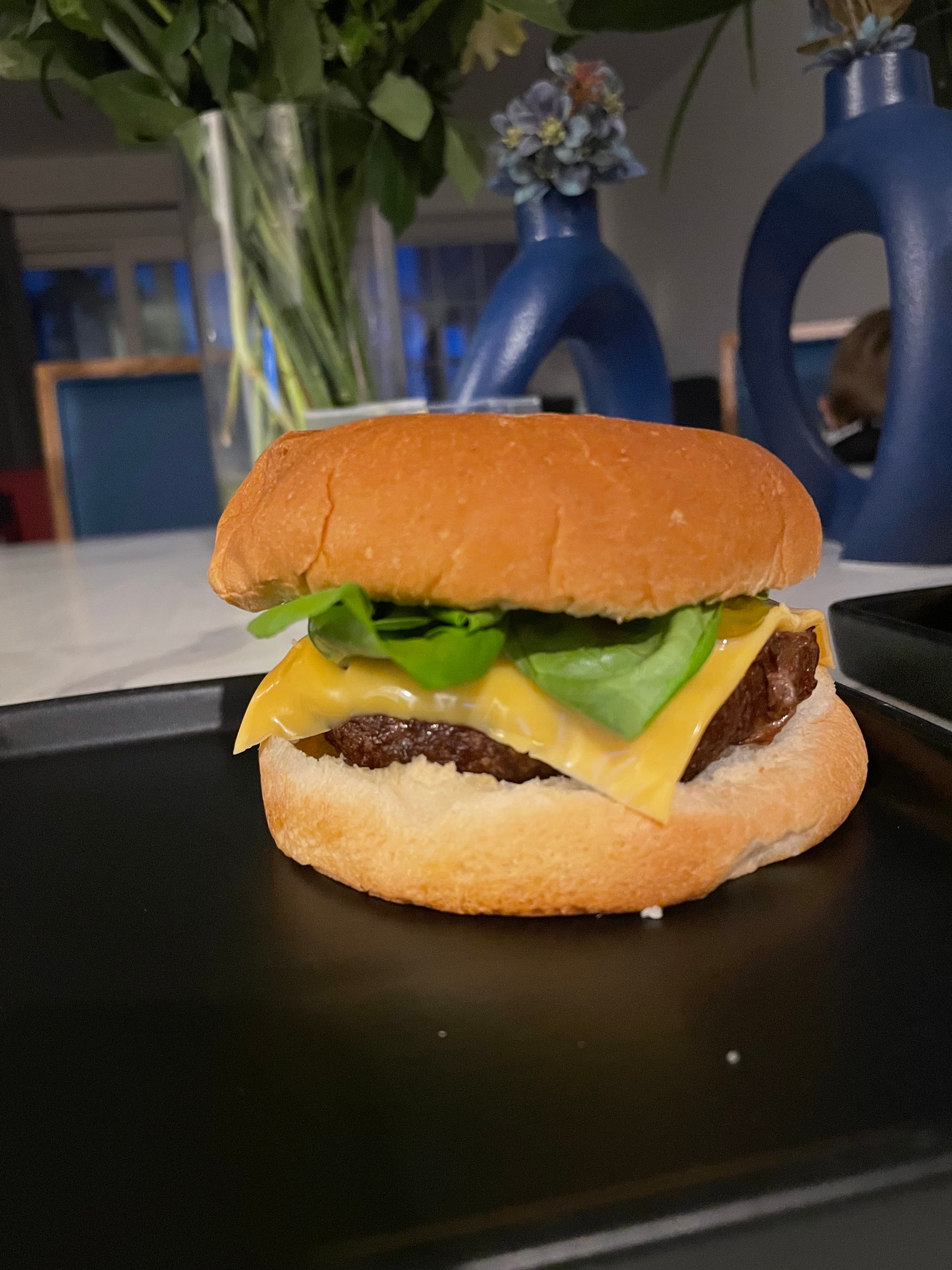 Cheeseburger with a beef patty, melted yellow cheese, and fresh lettuce on a soft bun.
